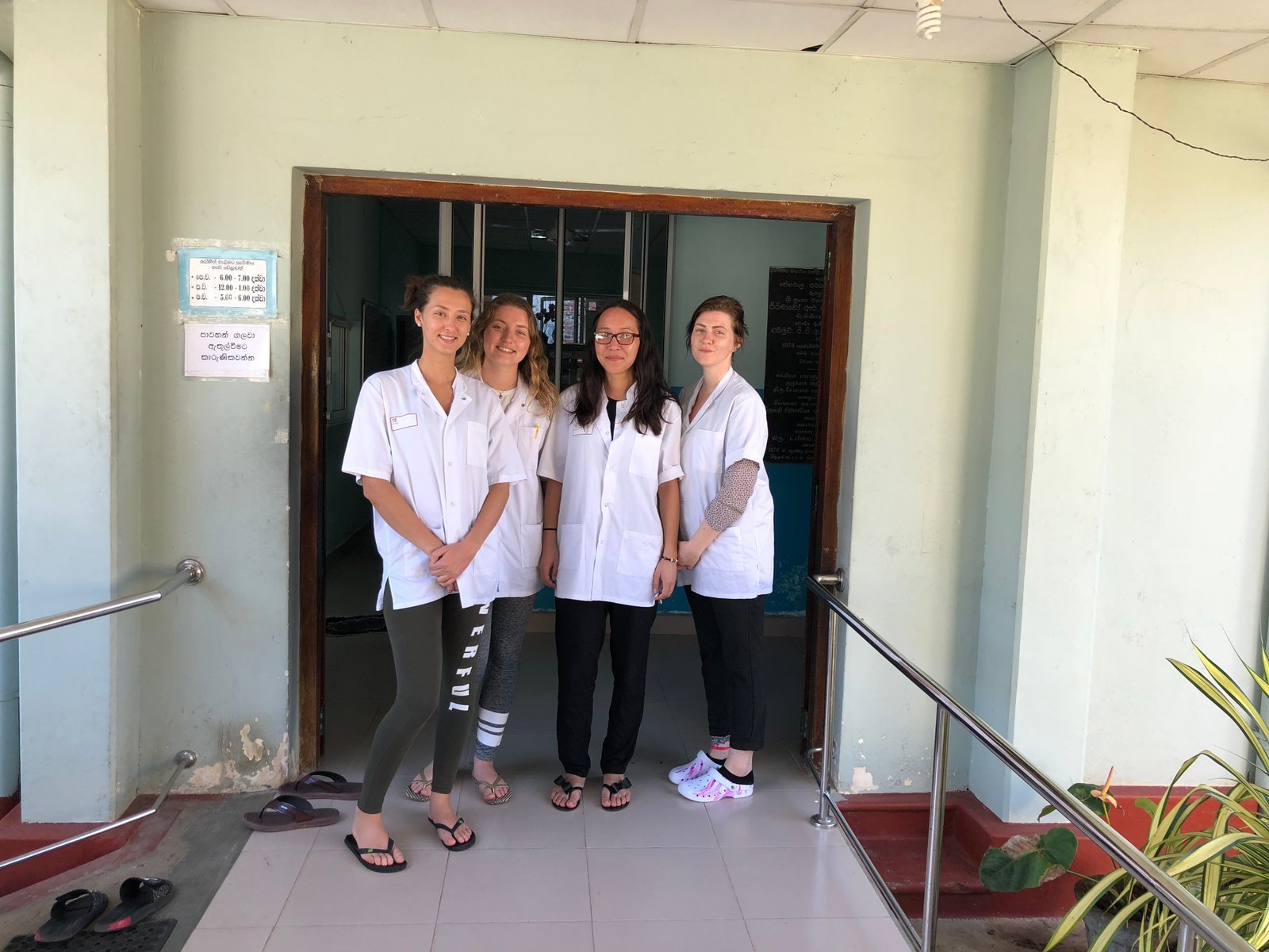 Four nursing students in white coats at the entrance to a rehabilitation centre in Sri Lanka