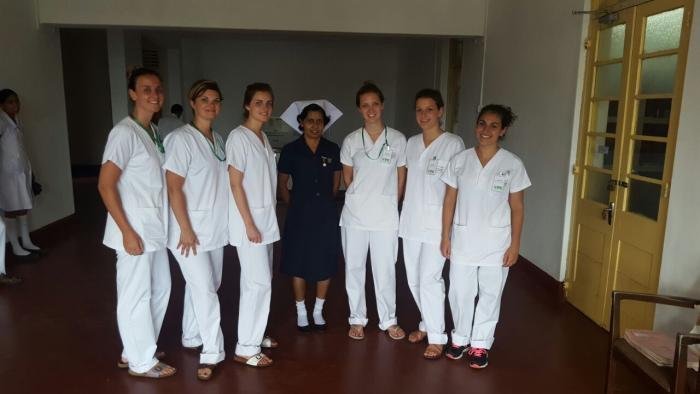 International nursing students standing with a registered ward nurse in uniform on a hospital corridor
