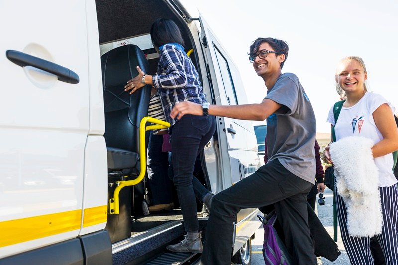 Students boarding a pre-booked programme minibus with their luggage